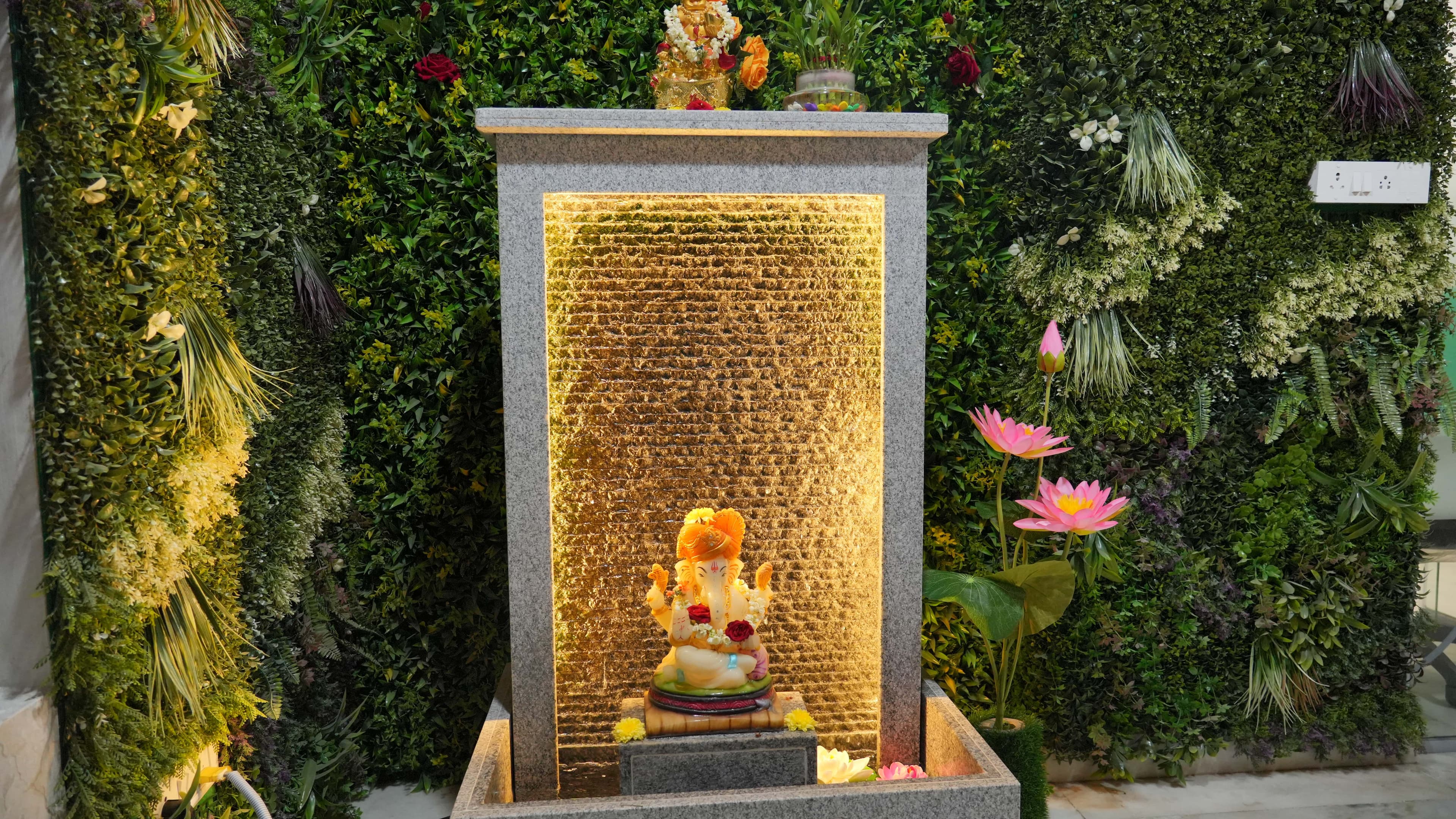Vastu-compliant water fountain with Ganesha idol and green plant wall at Spacio Workspace